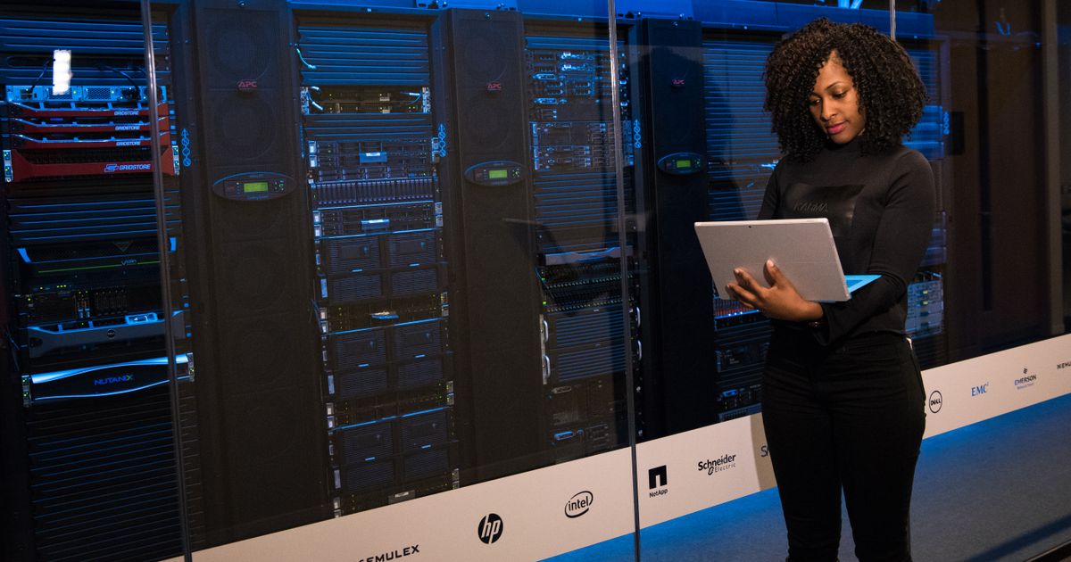 Engineer with a laptop beside server racks in a data center